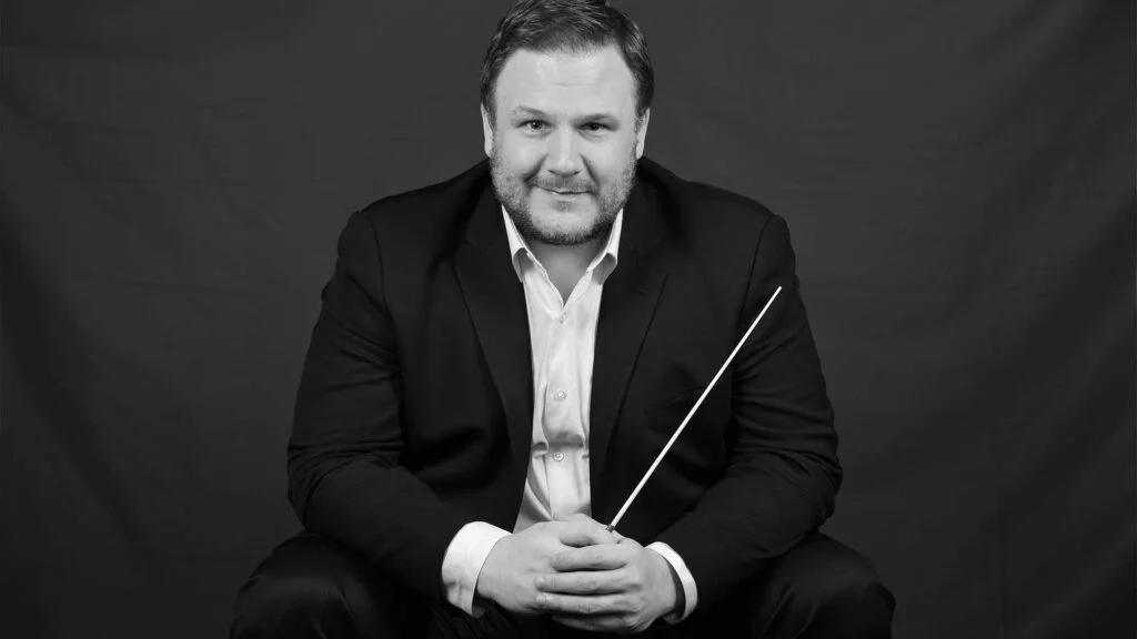 Black and white portrait of John Jesensky holding a conductor's baton