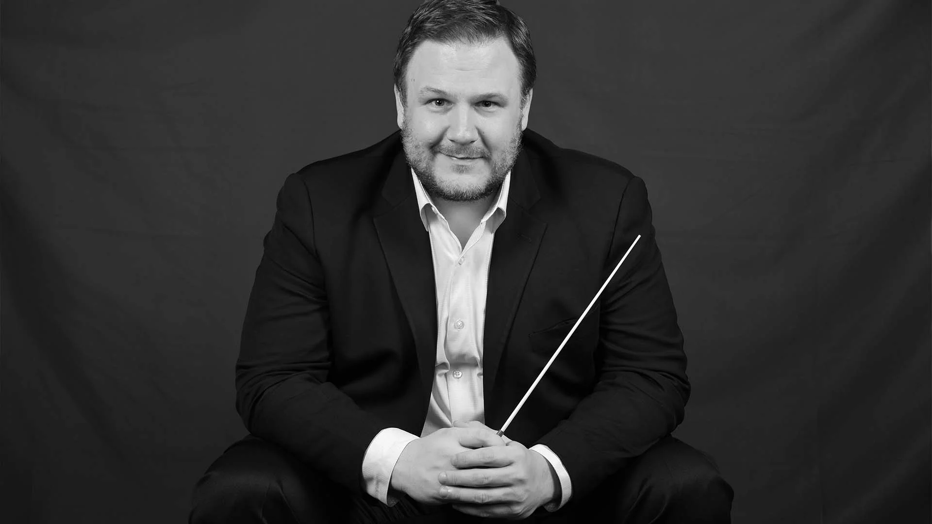 Black and white portrait of John Jesensky holding a conductor's baton