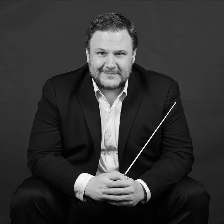 Square portrait of John Jesensky holding a conductor's baton, in black and white