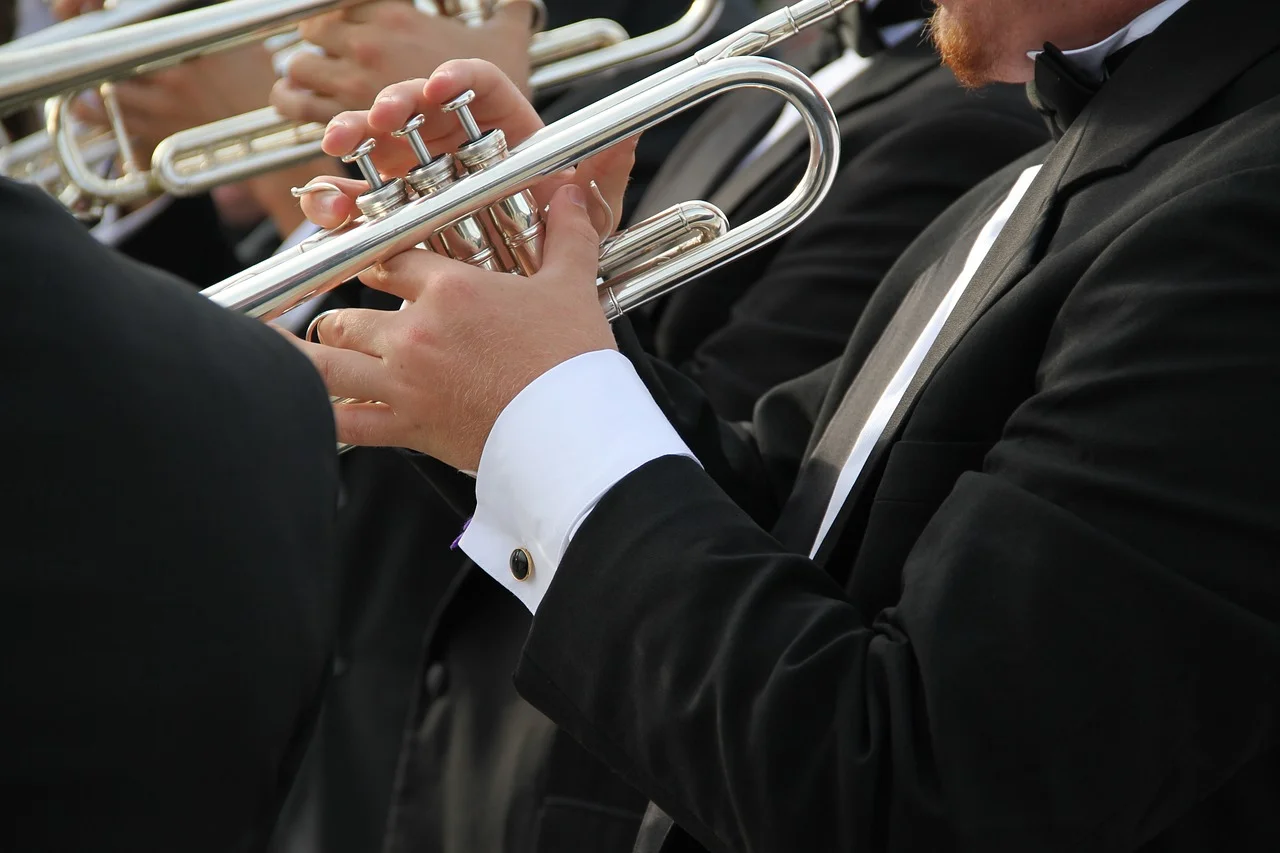 Trumpet players in tuxedos performing with an orchestra